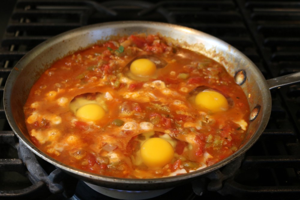 eggs just beginning to simmer in the tomato and chili sauce